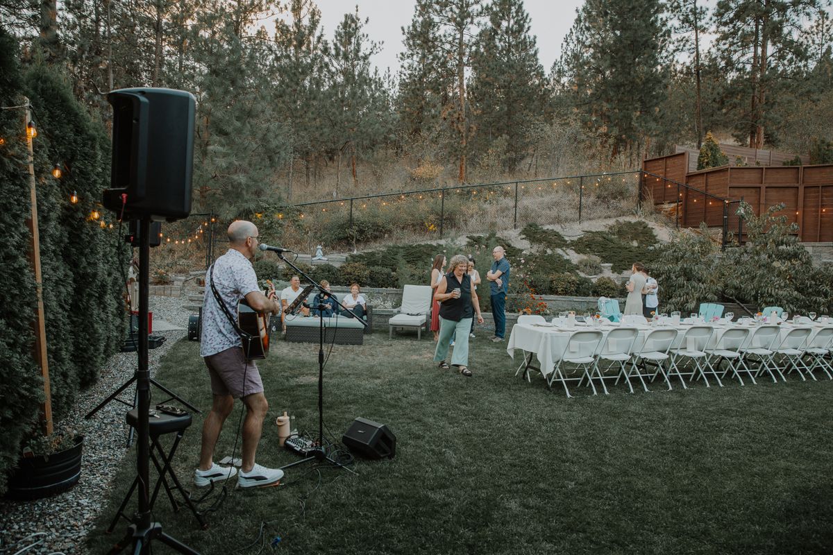 Colin playing beside a long dinner table set up on a lawn